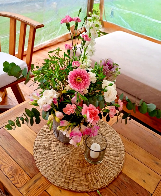 Arreglo rosa en mesa de madera con vela